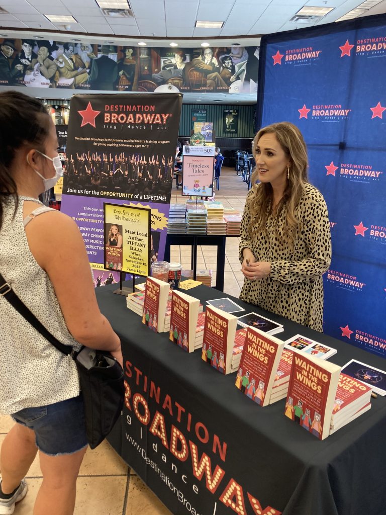 A woman standing next to a table with books on it.