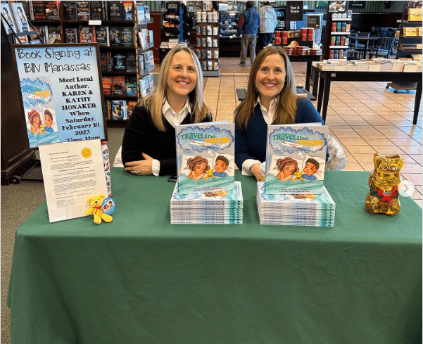 Two women sitting at a table with books.